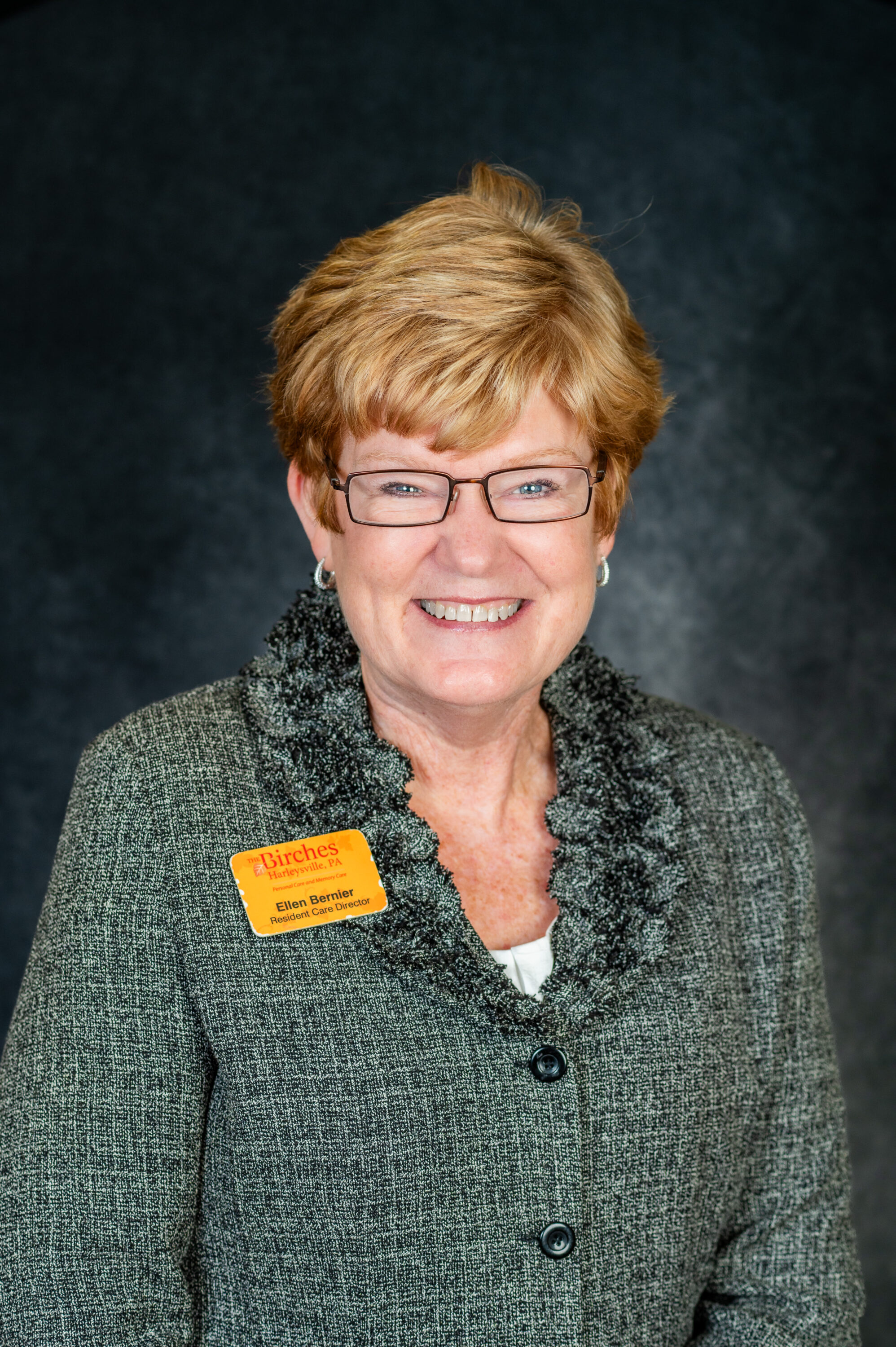 Smiling woman with glasses wearing name badge