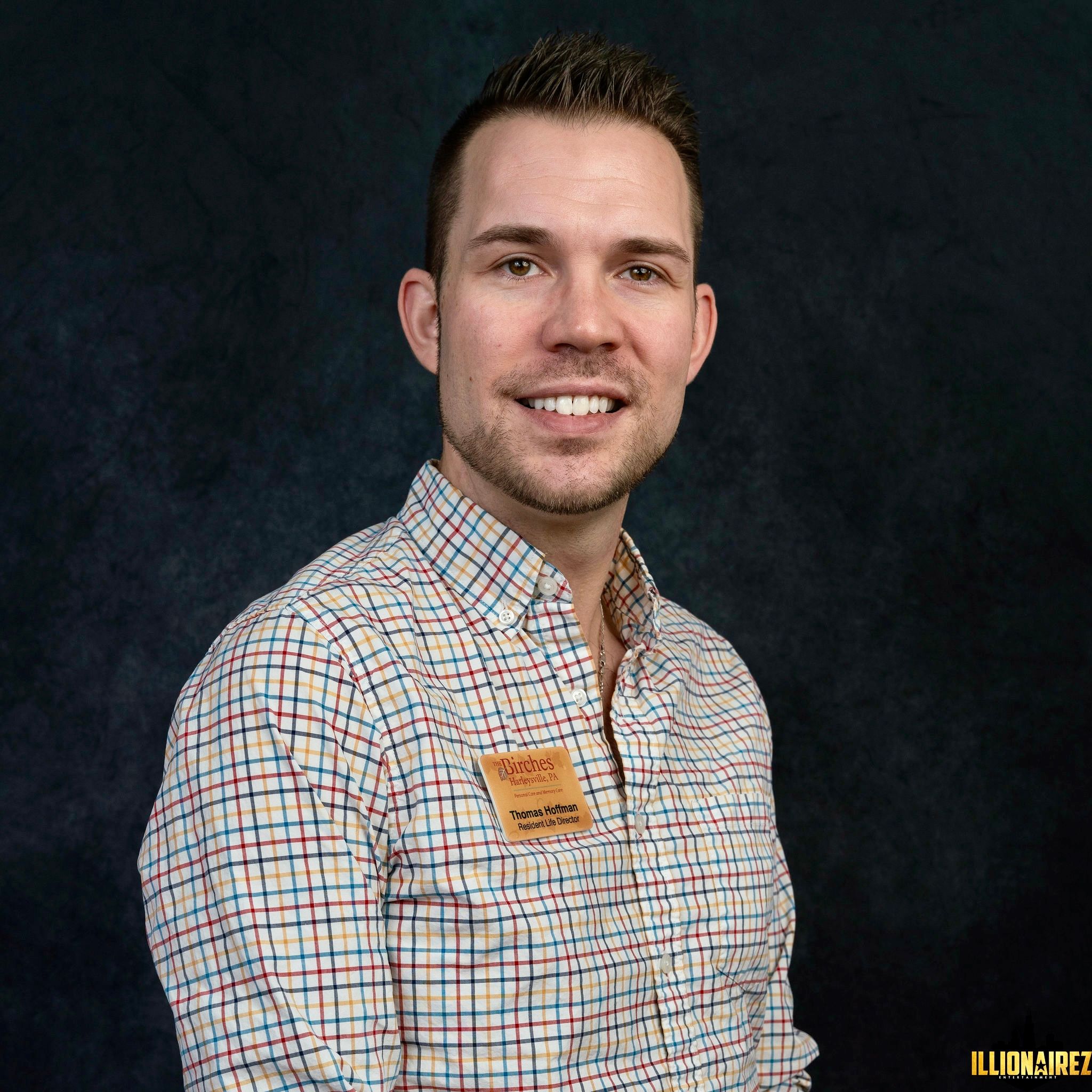 Smiling man wearing plaid shirt and name badge