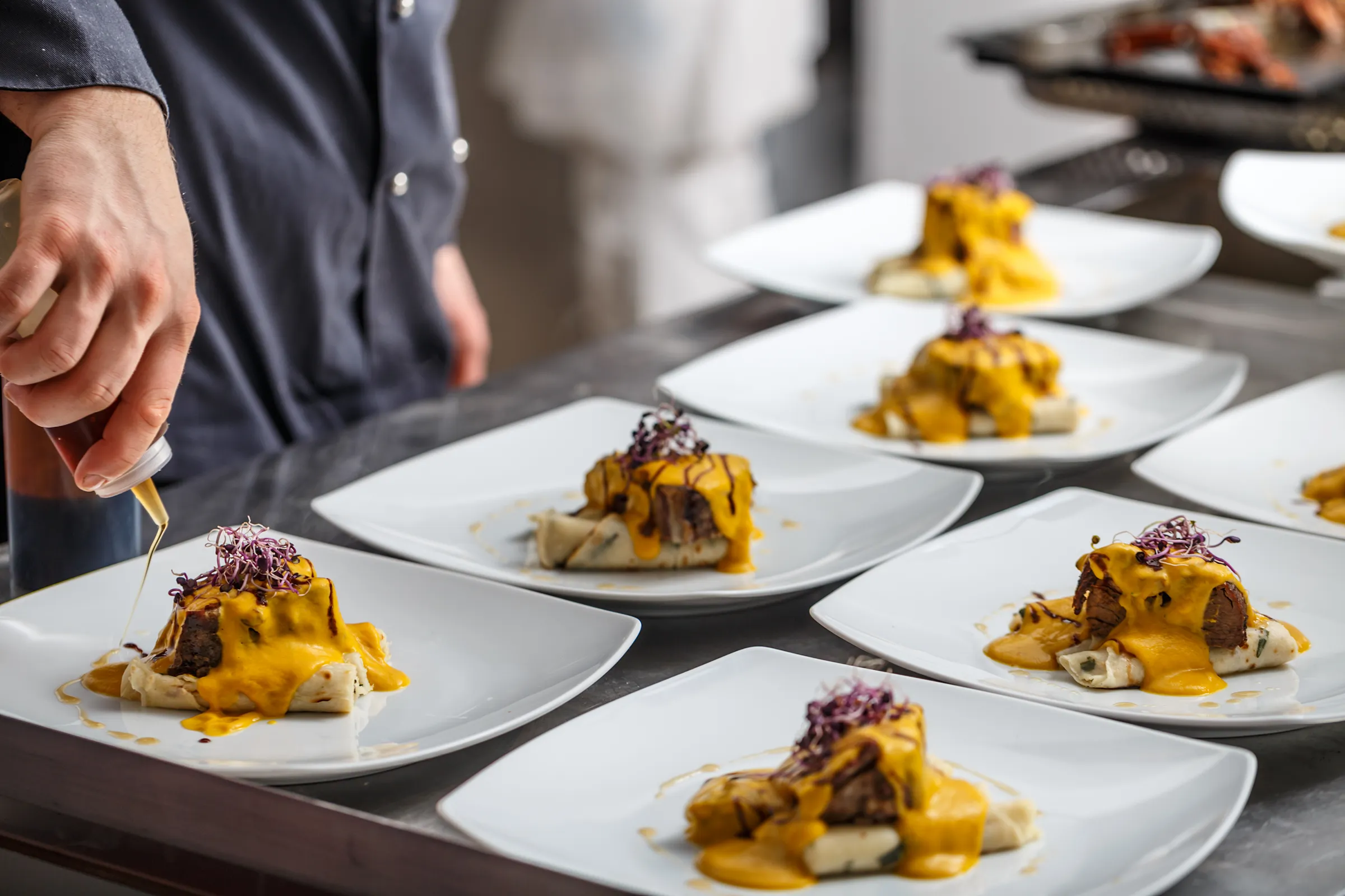 Chef plating gourmet beef with yellow sauce