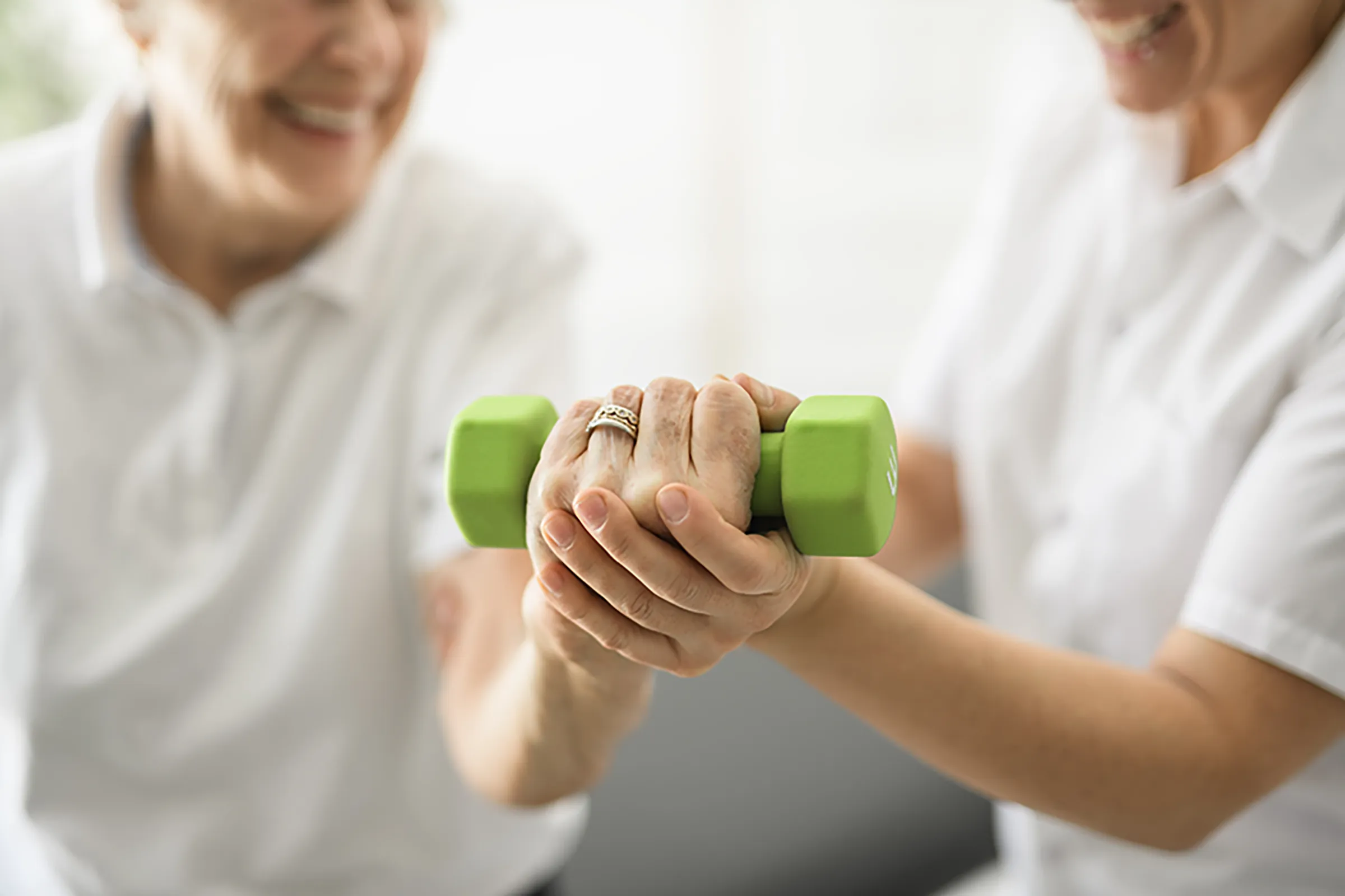 Caregiver assisting senior with dumbbell exercise